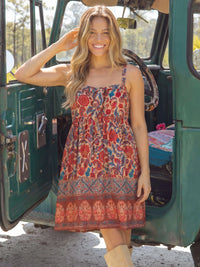 Woman in a floral dress standing next to an open green vehicle.
