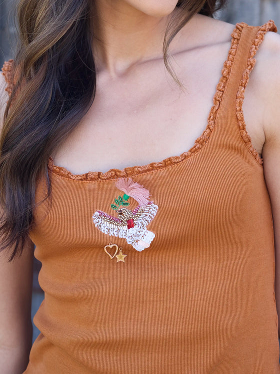 Brown tank top with floral embroidery and heart design on a blurred background
