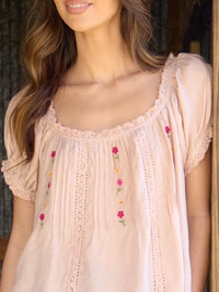 Beige embroidered top worn by a person with a blurred background