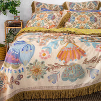 Floral patterned bedding set on a bed with a side table and plants in the background.