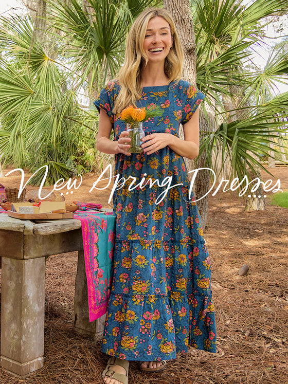 Woman in a floral dress holding flowers, with text 'New Spring Dresses' and palm leaves in the background.