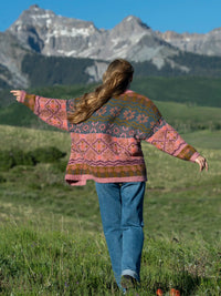 image of a girl running through a field with a pink sweater