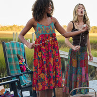 Two women in colorful dresses standing outdoors with a scenic background