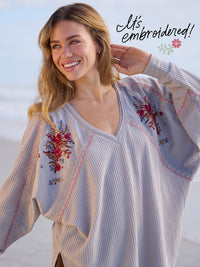 Woman wearing an embroidered blouse with a clear sky background