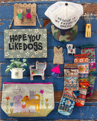 Collection of dog-themed products including a cap, socks, and pouches on a wooden surface.
