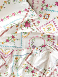 Collection of embroidered sheets with floral patterns on a white background