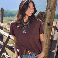 Girl in a brown tee in front of a wooden fence