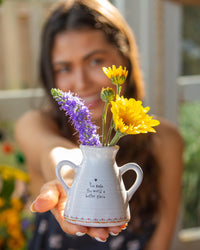 Woman holding a vase with flowers outdoors
